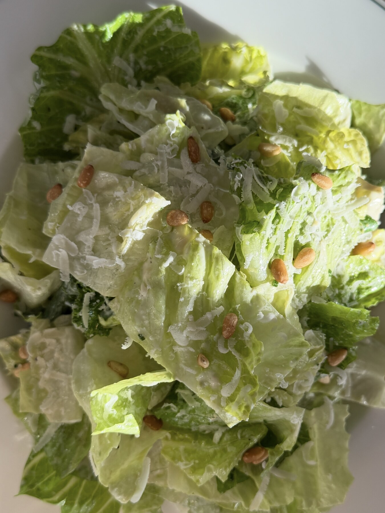Romansallad i caesardressing med pinjenötter och riven manchego