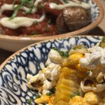Grillad majskolv i mönstrad skål, täckt med rökt paprikasmör, popcorn och gräslök