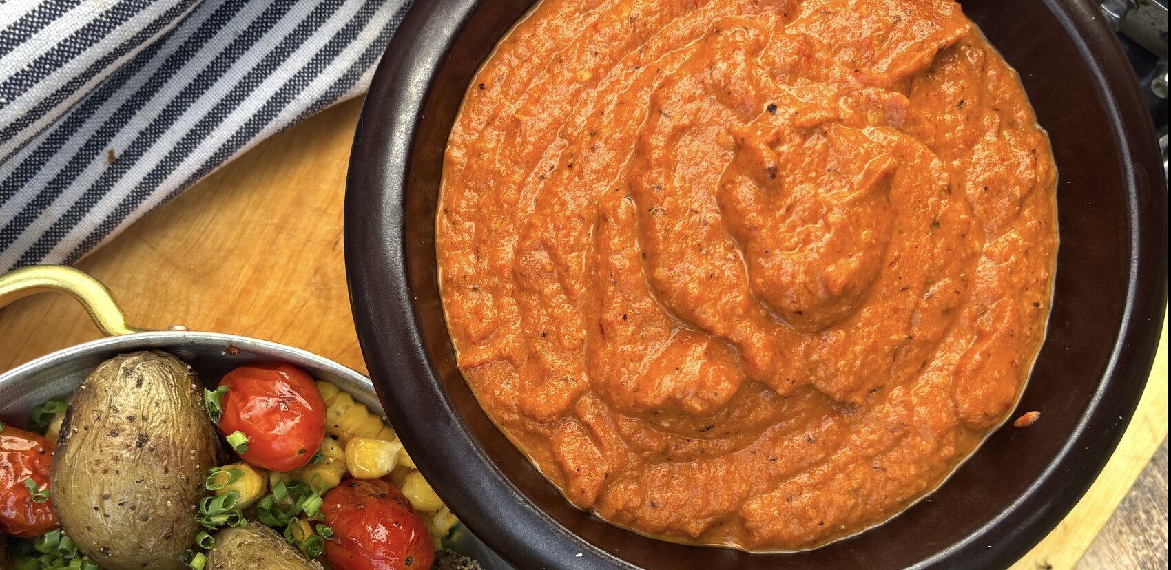 Romesco i svart skål med grillad färskpotatis