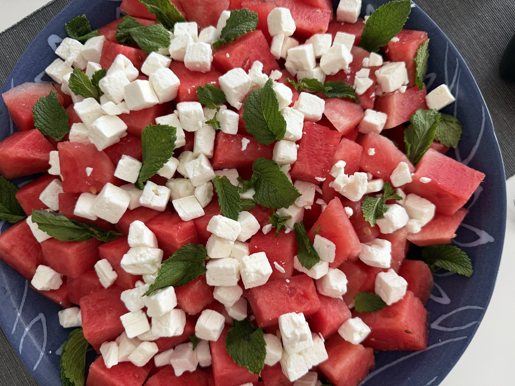 Vattenmelonsallad i blå skål med tärnad vattenmelon, tärnad fetaost och färska myntablad