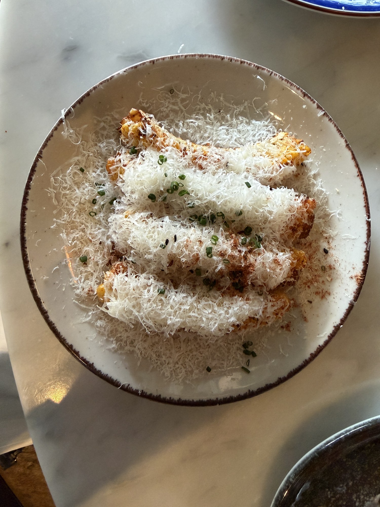 Friterade majshalvor täckta med finriven manchego, pimentón och gräslök i en skål