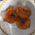 Tre stora skalade räkor i blank orangeröd salsa brava på en blomstermönstrad tallrik