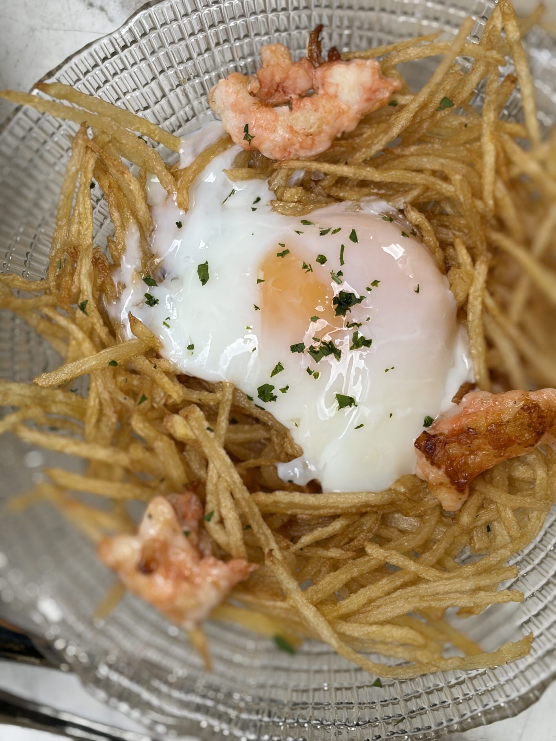 Huevos Rotos med pocherat ägg, friterad strimlad potatis och räkor
