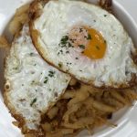 Huevos Rotos med stekta ägg ovanpå knaperfriterade miniräkor