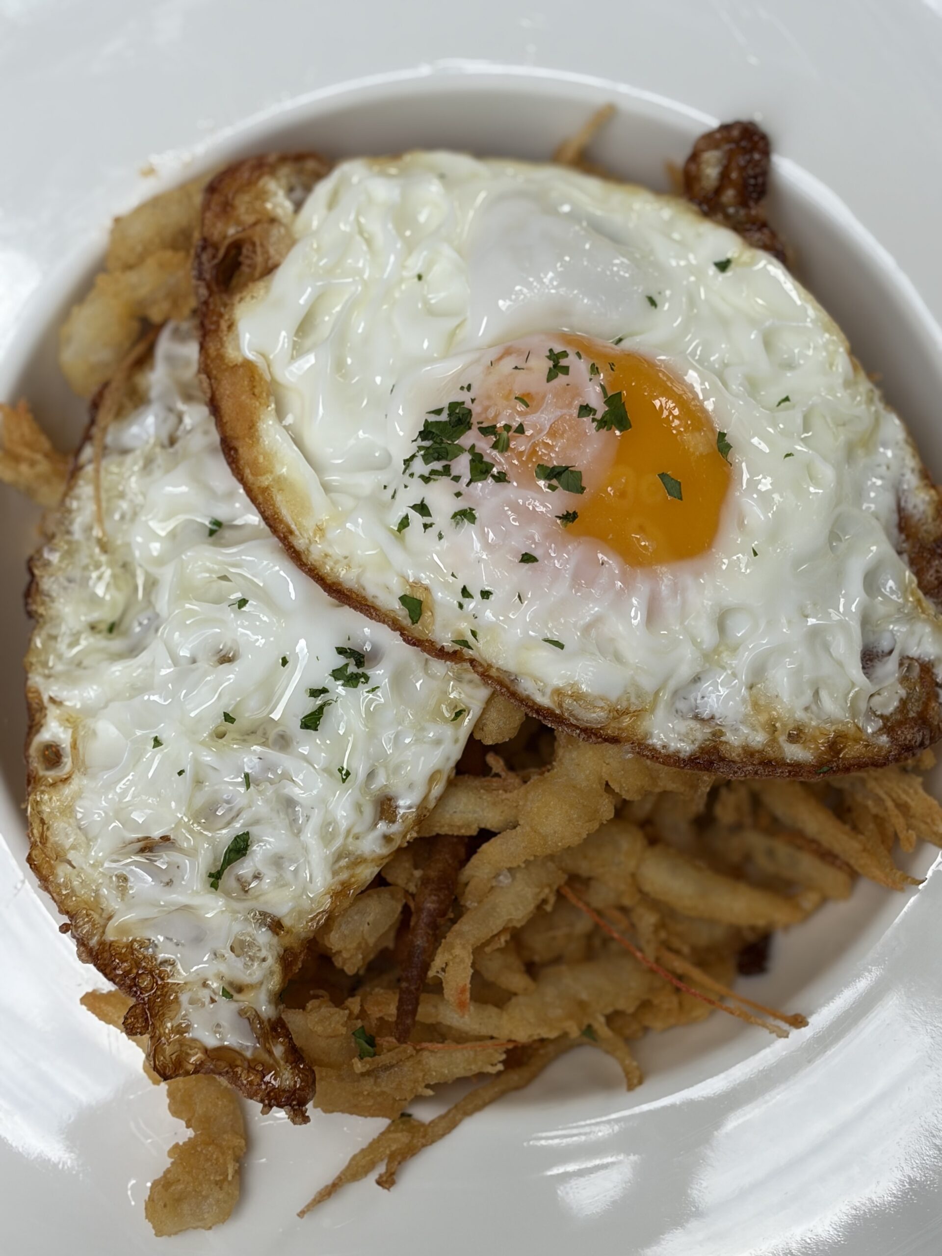 Huevos Rotos med stekta ägg ovanpå knaperfriterade miniräkor