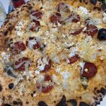 Vit pizza med skivad chorizo, klickar av getost, hyvlad lök och fänkålsfrö