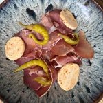 Serranoskinka med skivor av paprikasmör och gröna peperoncini