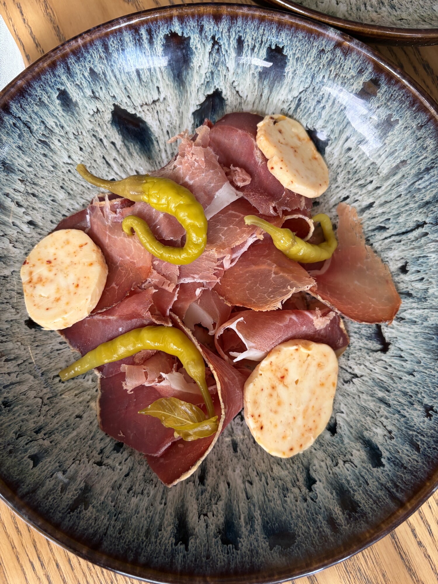 Serranoskinka med skivor av paprikasmör och gröna peperoncini