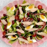 Salade niçoise med tonfisk, ansjovis, ägg och oliver på ett rosa fat