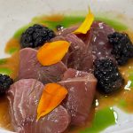 Tonfiskcrudo med björnbär, örtolja och tagetesblad i en djup tallrik