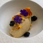 Quenelle av vispad anklever med torkade svarta oliver, poppat ris och ätbara blommor